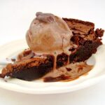 Flourless Chocolate Brownie Cake with ice cream scoop on top of it.