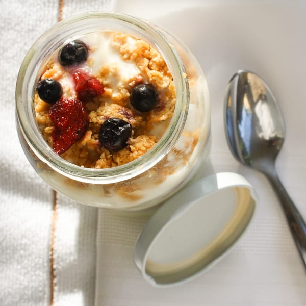 graham cracker Triple terry yogurt parfait in a glass pot with a spoon next to it.