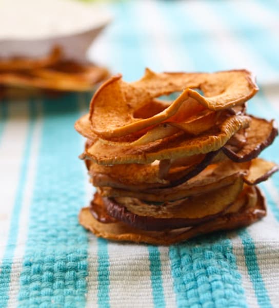 Stack of apple cinnamon chips on a bleu table cloth.