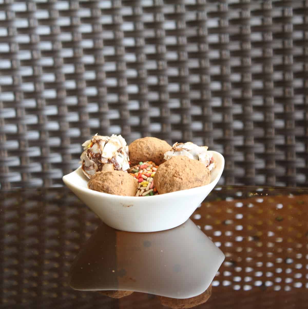 A white bowl with rum balls in it.