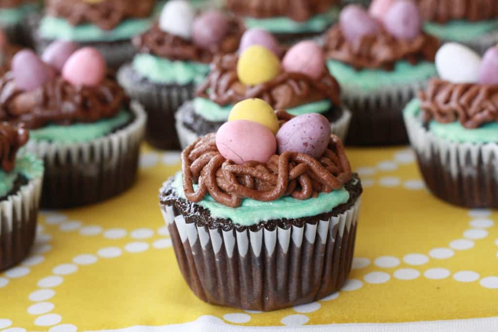 Bird's nest easter cupcakes on yellow tablecloth.