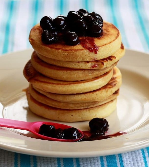 Side shot of a stack of vanilla pancakes with blueberry sauce.