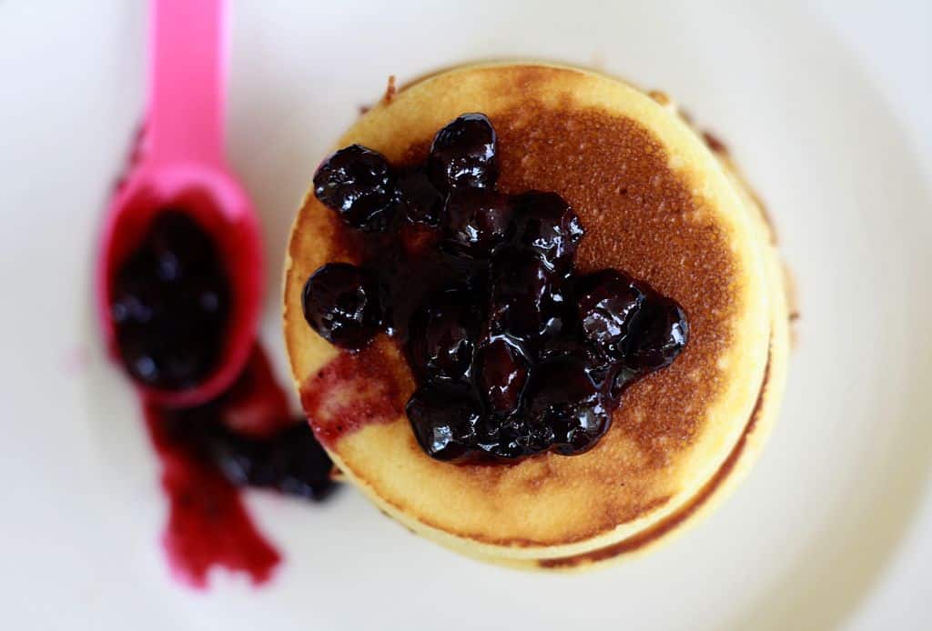 Top down shot of fluffy vanilla pancakes with blueberry sauce.