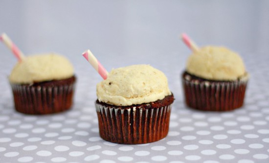 Three root beer float cupcakes on a table.