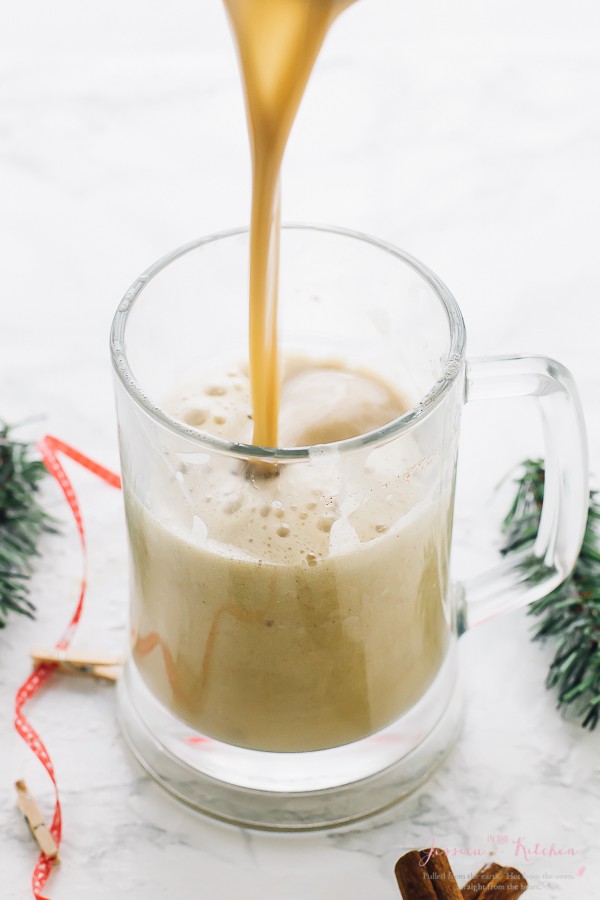 Pouring spiced eggnog into a glass mug. 