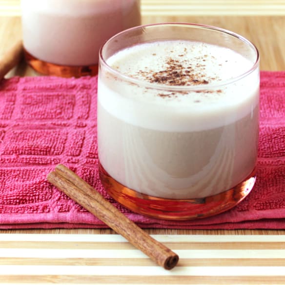 Boozy Christmas Spiced Eggnog with a cinnamon stick next to it.