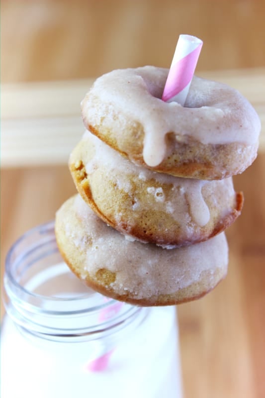 A stack of gingerbread doughnuts around a straw.