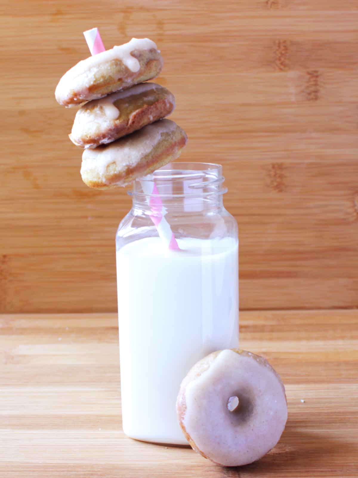 Gingerbread Doughnuts on straw over a glass of milk.