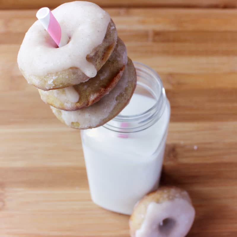 Three doughnuts on a straw in some milk.