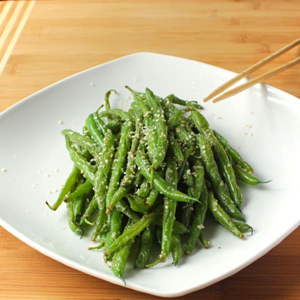 Green beans in a white dish with chopsticks.