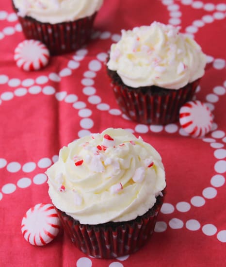 Three chocolate peppermint swirl cupcakes on a red tablecloth.