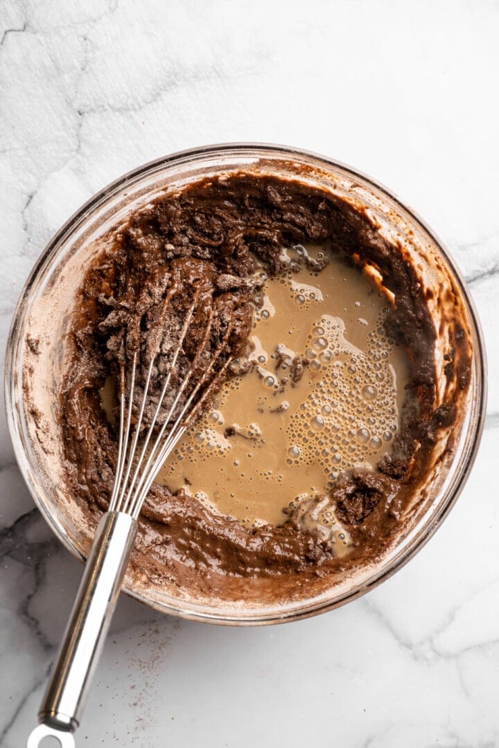 Whisk in bowl with ingredients for chocolate peppermint cupcakes.