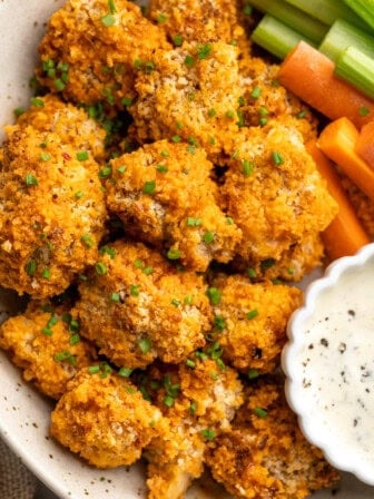 Platter of cheesy Buffalo cauliflower wings with celery, carrots, and ranch.