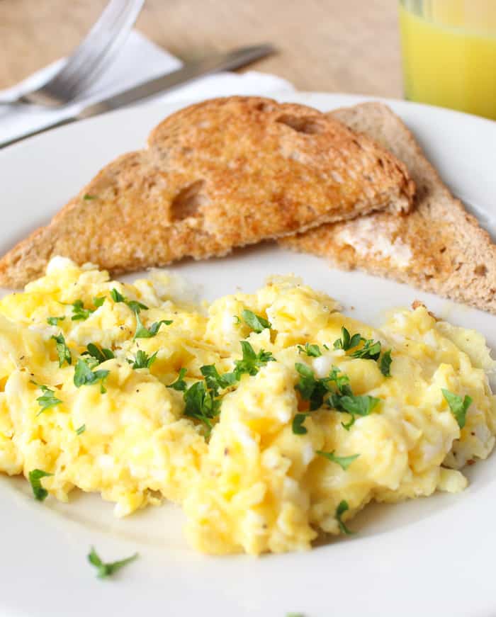 Scrambled Eggs on a white plate with toast.
