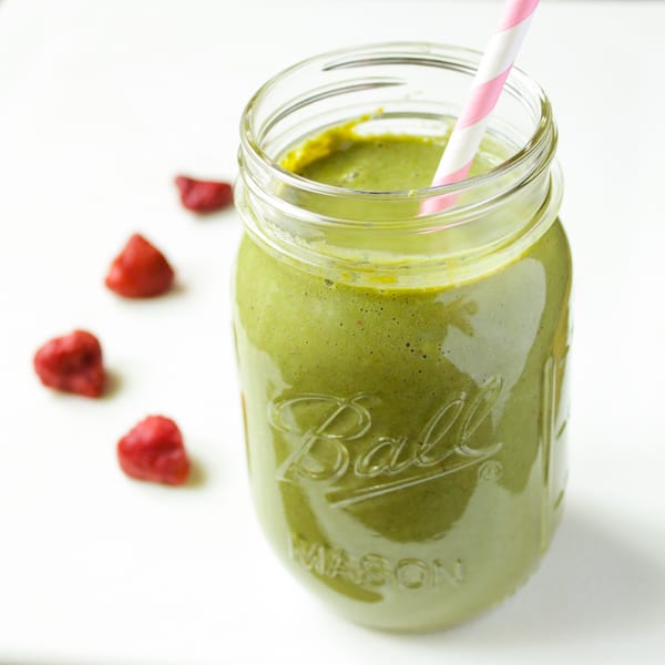 Strawberry kale smoothie in mason jar with pink and white striped straw