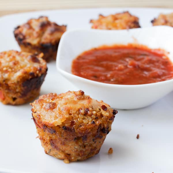 Quinoa pizza bites on a white dish with dipping sauce.