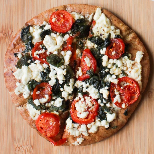 Overhead shot of feta pizza on a wooden table.