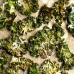 Cheesy kale chips on parchment paper. - 13