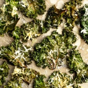 Cheesy kale chips on parchment paper.