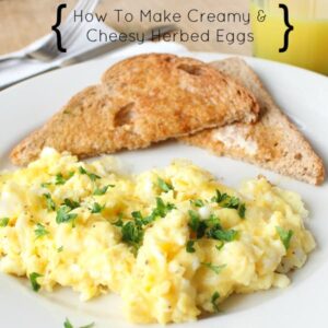 Herby scrambled eggs and toast on a white plate.