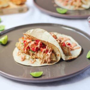 Side on shot of fish tacos on a grey plate.