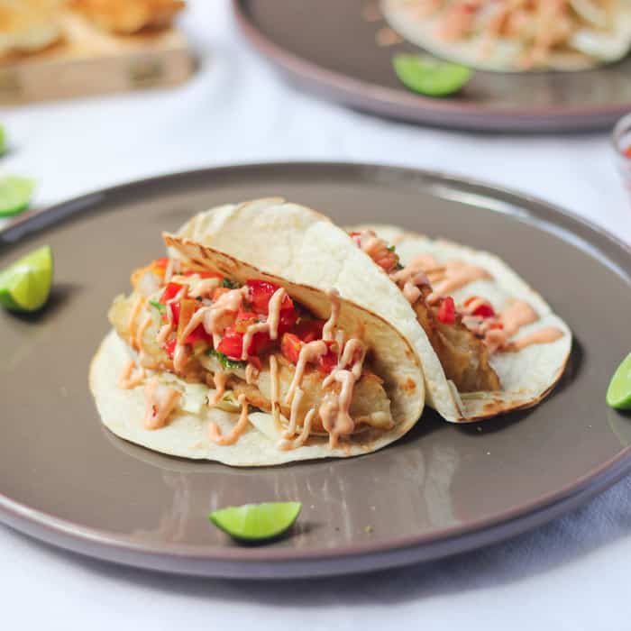 Beer battered fish tacos with sriracha mayo on a grey plate.