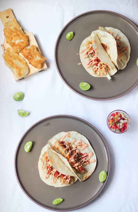 Top down shot of fish tacos on grey plates.