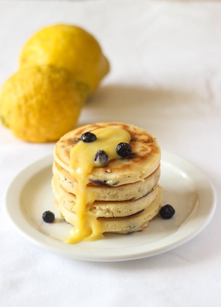 Stack of blueberry lemon pancakes with lemon curd on a white plate.