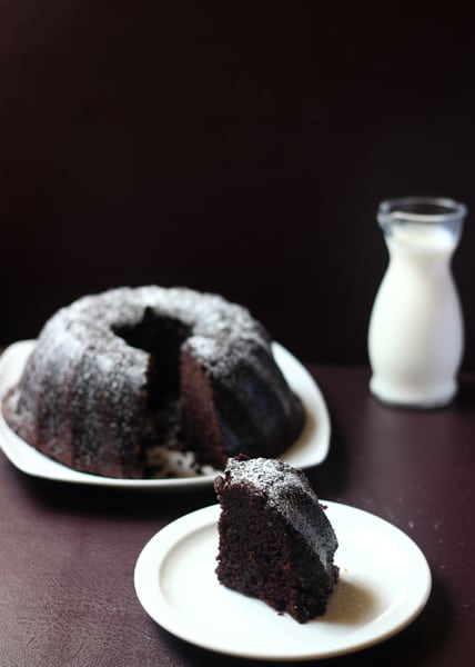 Chocolate Cake with slice taken out and glass of milk.