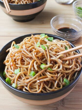 Sesame noodles in black and brown bowl with chopsticks in them