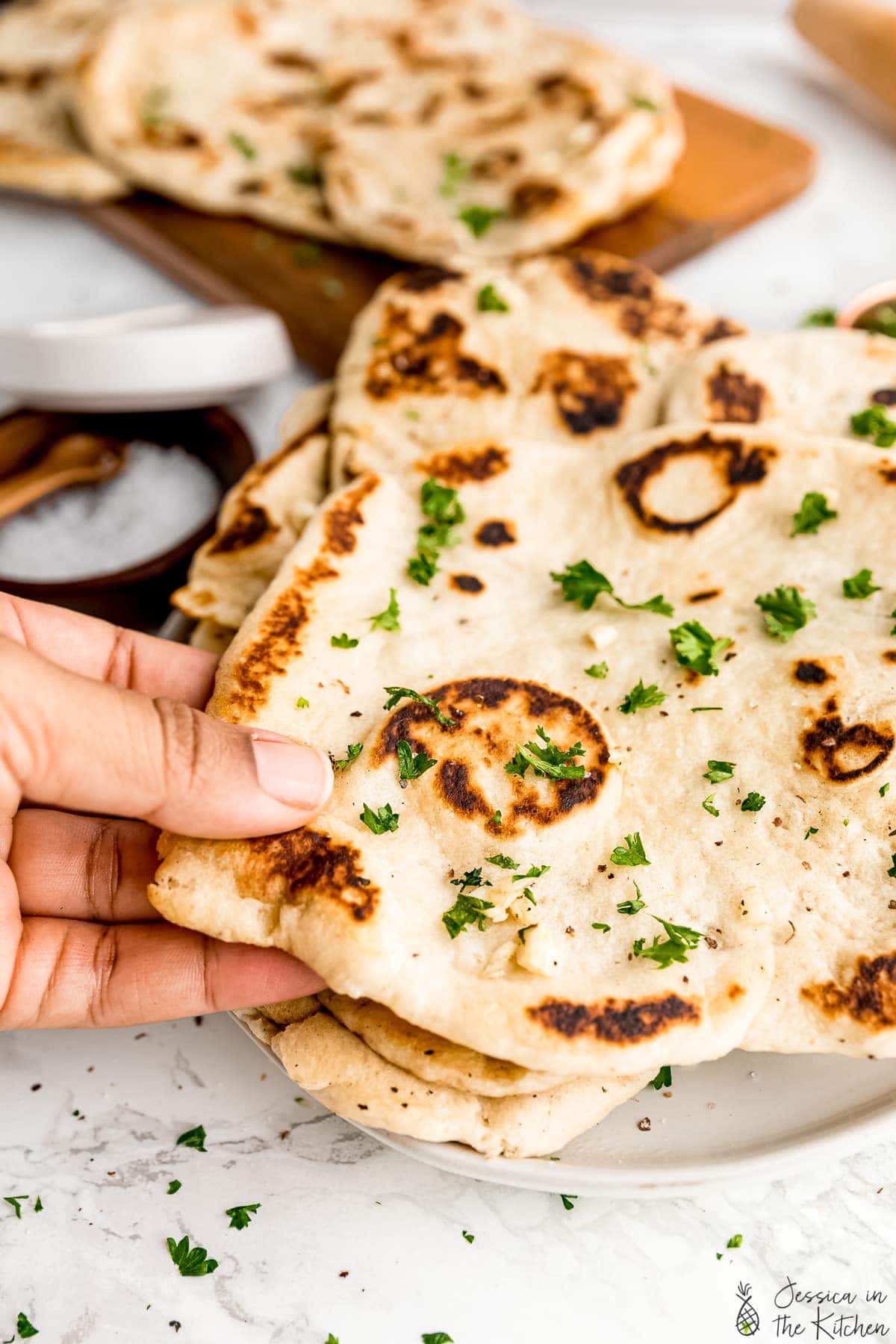 A hand holding a loaf of naan.