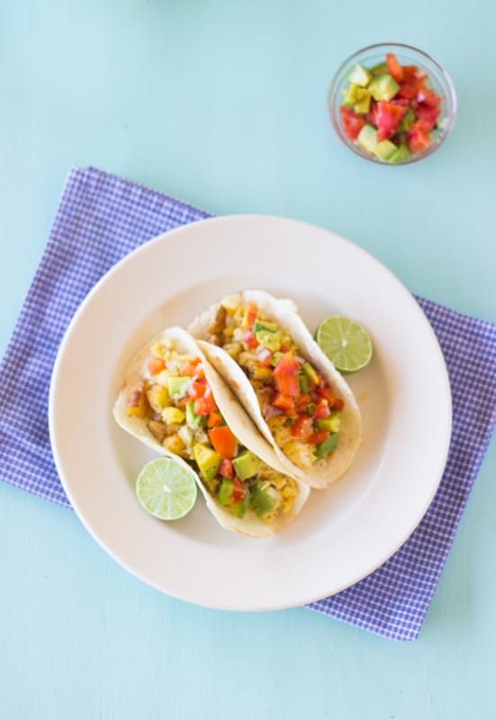 Top down shot of breakfast tacos on a white plate.