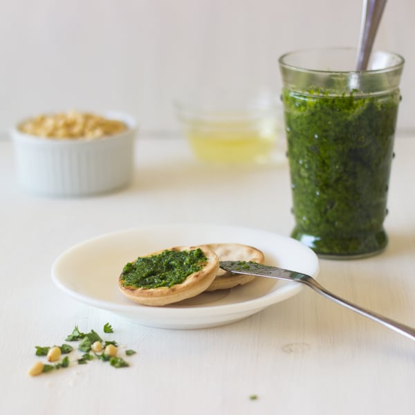 Parsley pesto on crackers with a jar of pesto in the background.