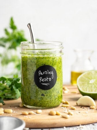 Jar of parsley pesto on cutting board.