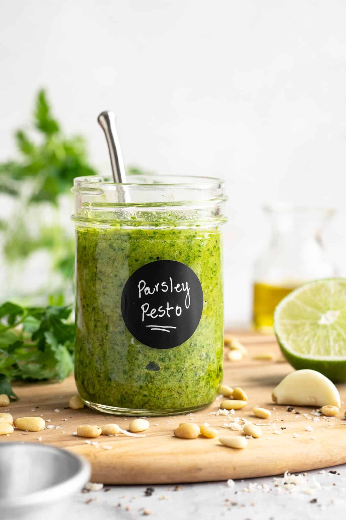 Jar of parsley pesto on cutting board.