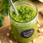 Jar of homemade parsley pesto with spoon.