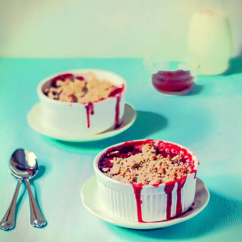 Strawberry Crumble in ramekins on a blue table.