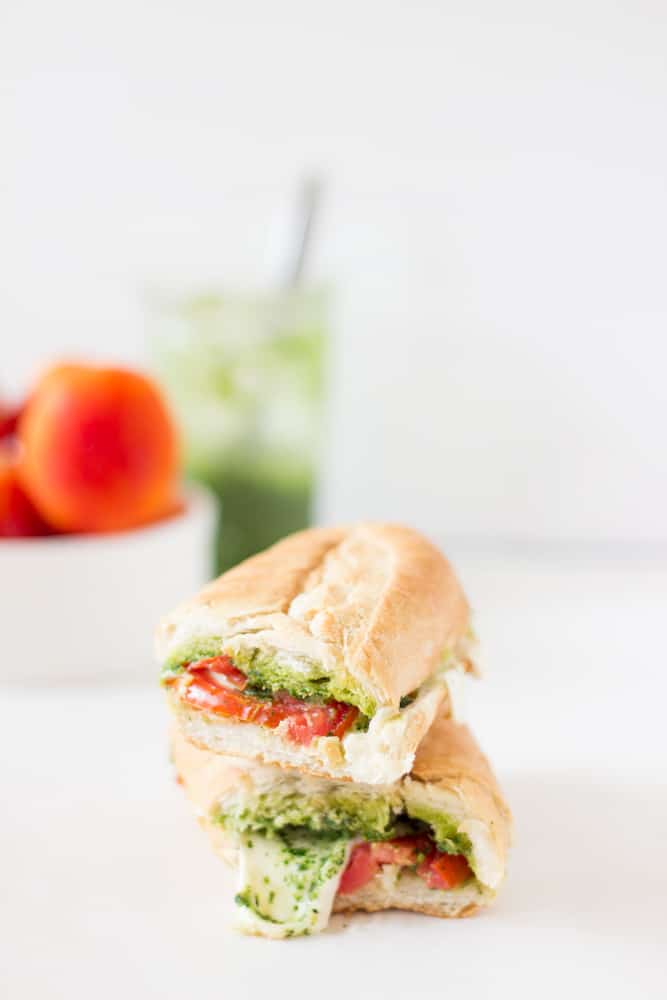 Caprese Sandwich cut in half on a white table. 