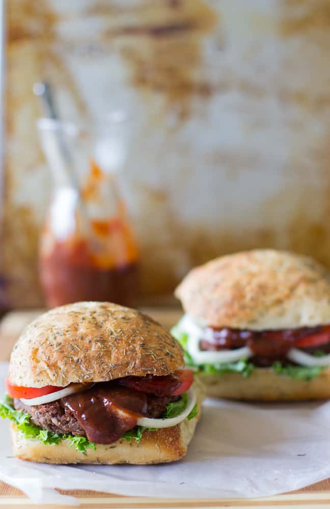 Side shot of two black bean and quinoa burgers on parchment. 