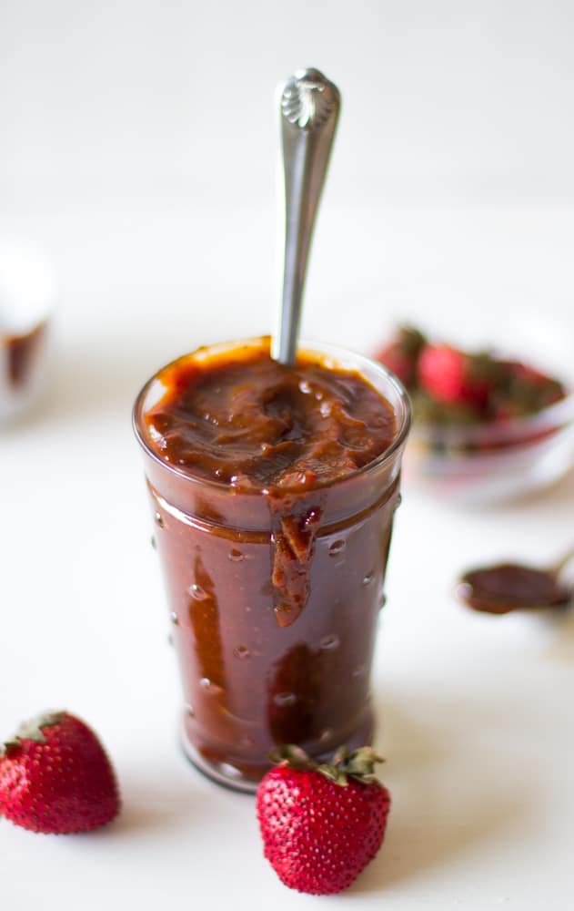 Roasted strawberry barbecue sauce in a glass with a spoon in it. 