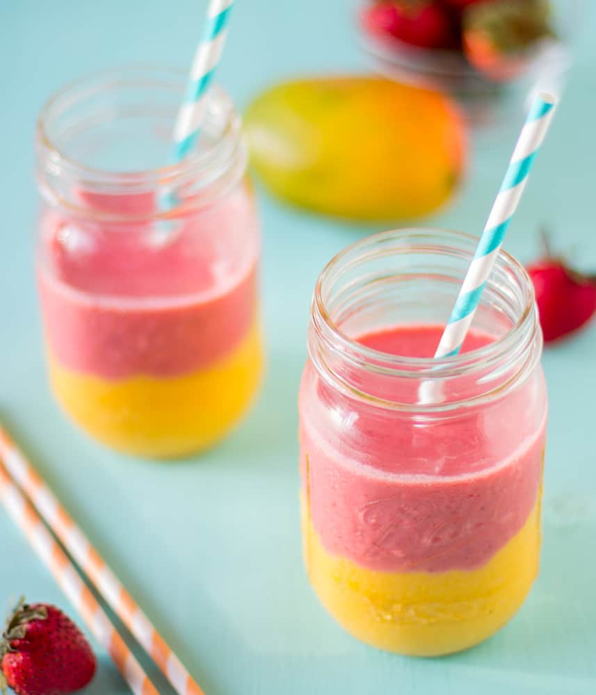 Two strawberry mango smoothies on a blue table.