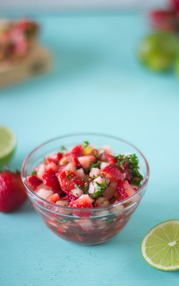 Strawberry salsa in a glass bowl on a blue table.