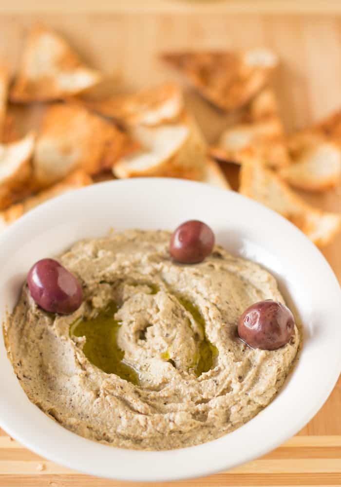 Baba ghanoush in a white bowl with olives. 