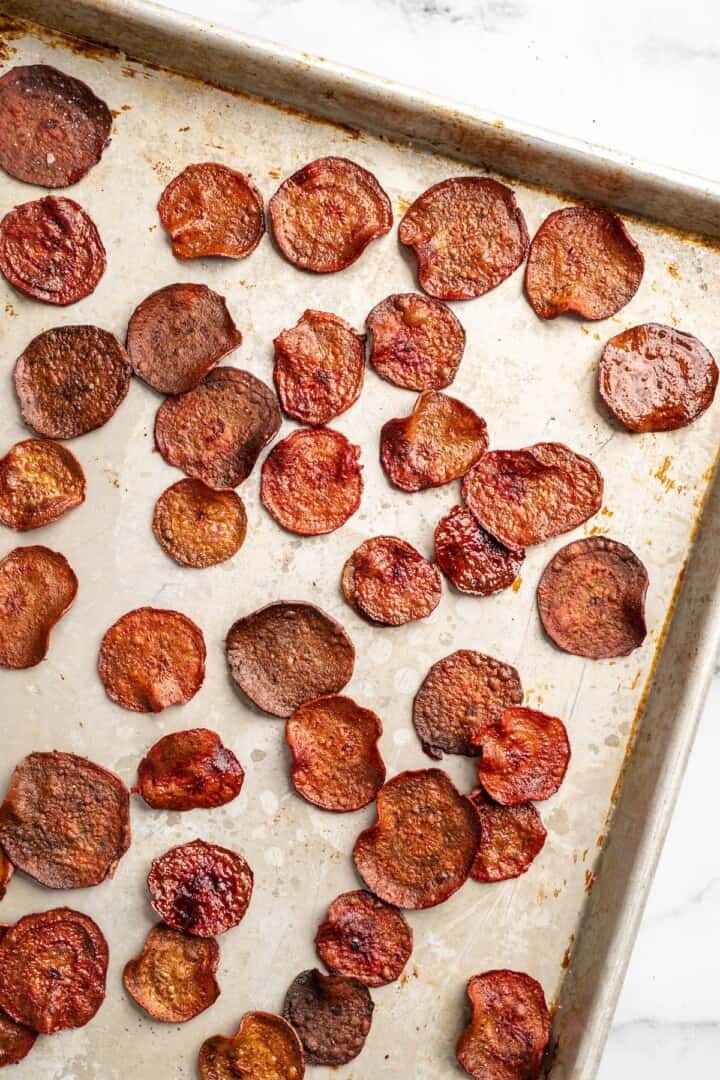 Overhead view of baked beet chips on sheet pan