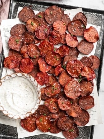 Overhead view of beet chips on sheet pan with bowl of dip