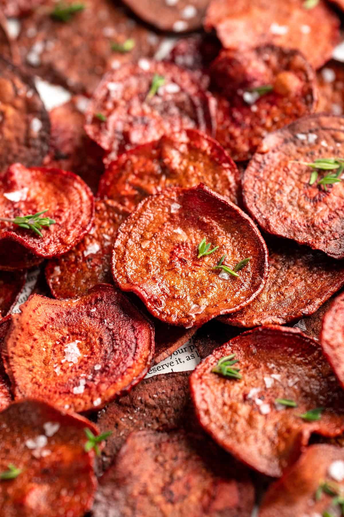 Closeup of baked beet chips topped with sea salt and fresh thyme leaves