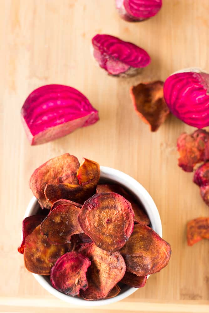 Top down shot of beet chips in a ramekin on a wooden table.