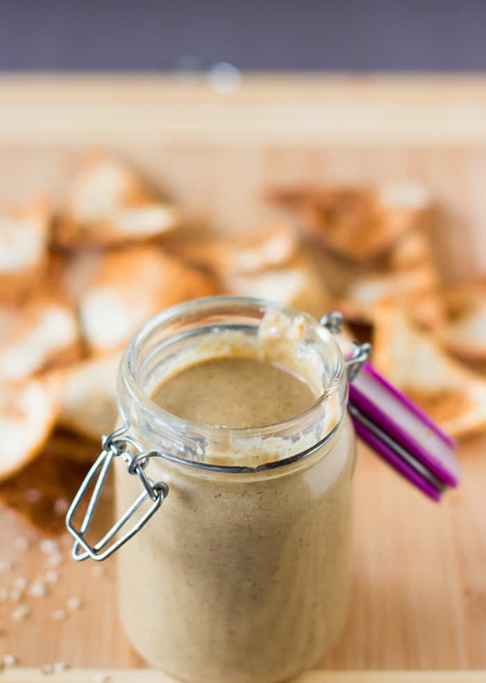 Tahini in a glass jar on a wood table top.