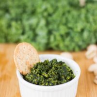 Bowl of pesto with a cracker dipped in.