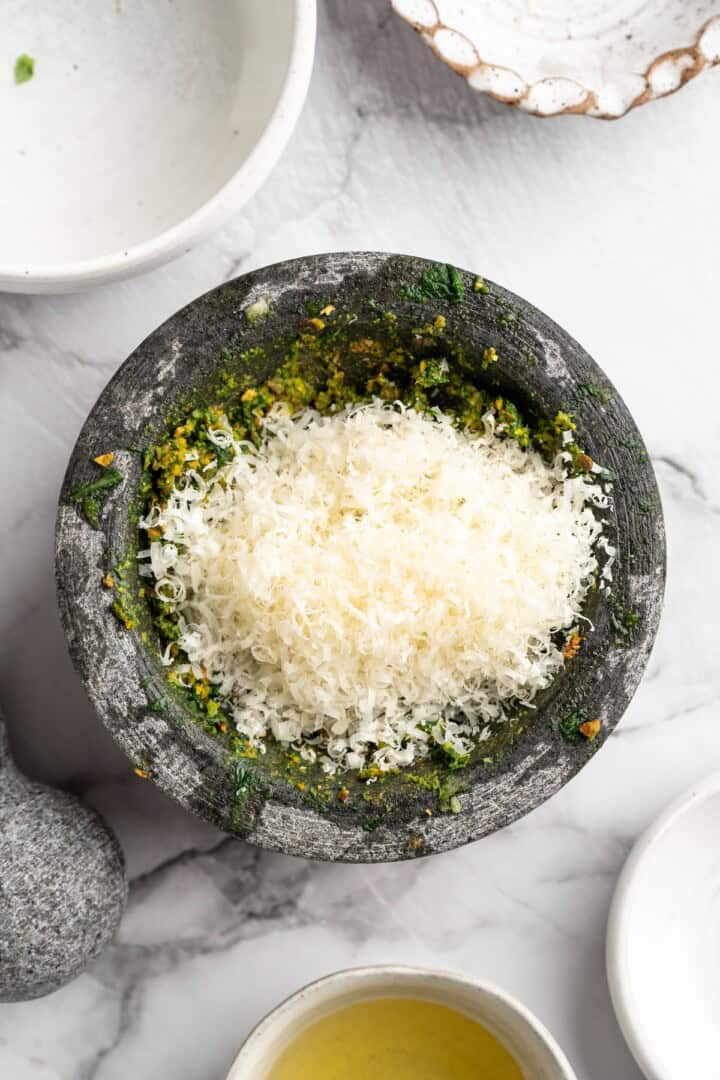 Pistachio pesto combines fresh basil leaves with nutty pistachios for a different spin on pesto. It's easy to make and so delicious! Vegan Parmesan added to pistachio pesto in mortar